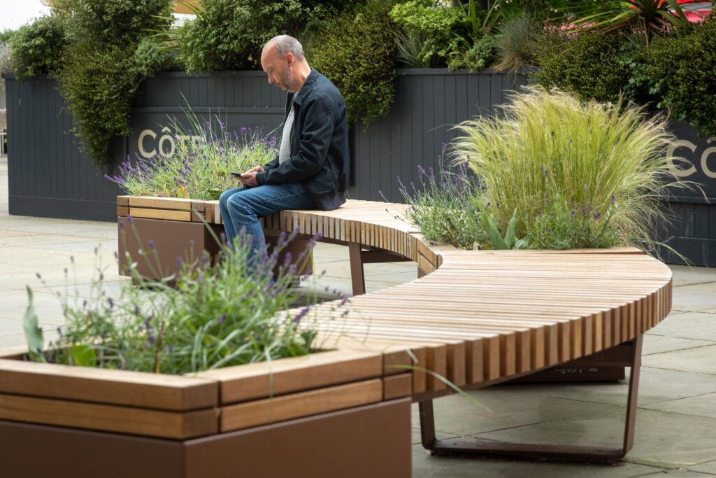 人手机上坐在布里斯托尔Quaker修道院的铁路长椅上